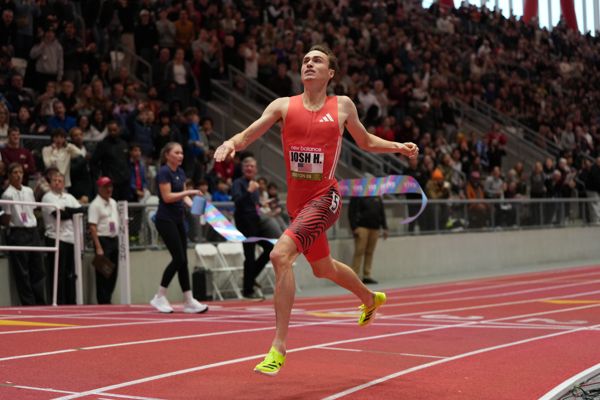 ** Runner crossing finish line on indoor track during record-breaking 800-meter race in Boston