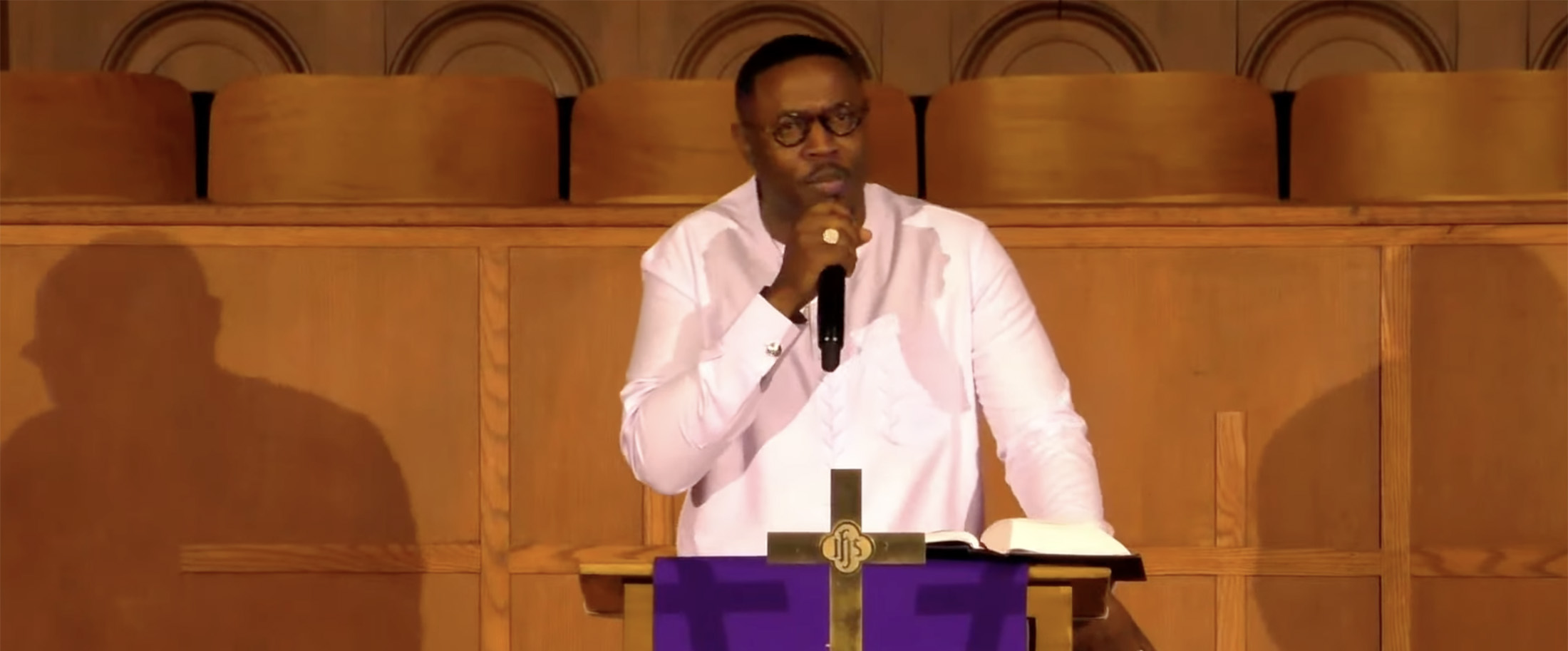 Pastor speaking from pulpit gesturing toward congregation during challenging sermon about compassion