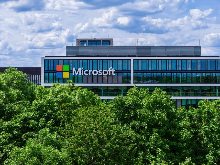 Modern data center with solar panels and wind turbines representing Microsoft's renewable energy achievement