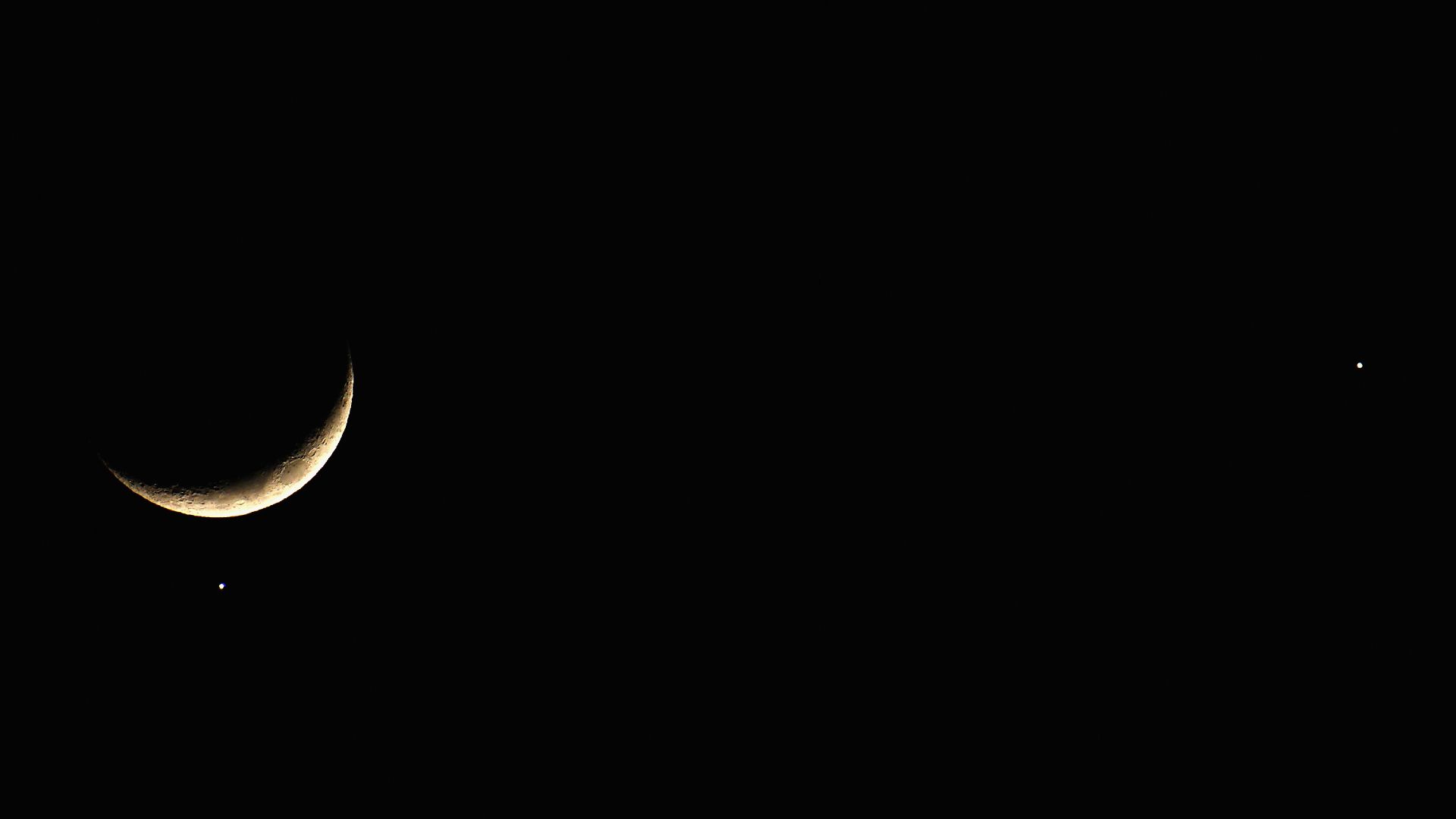 Crescent moon glowing in twilight sky above the horizon in England