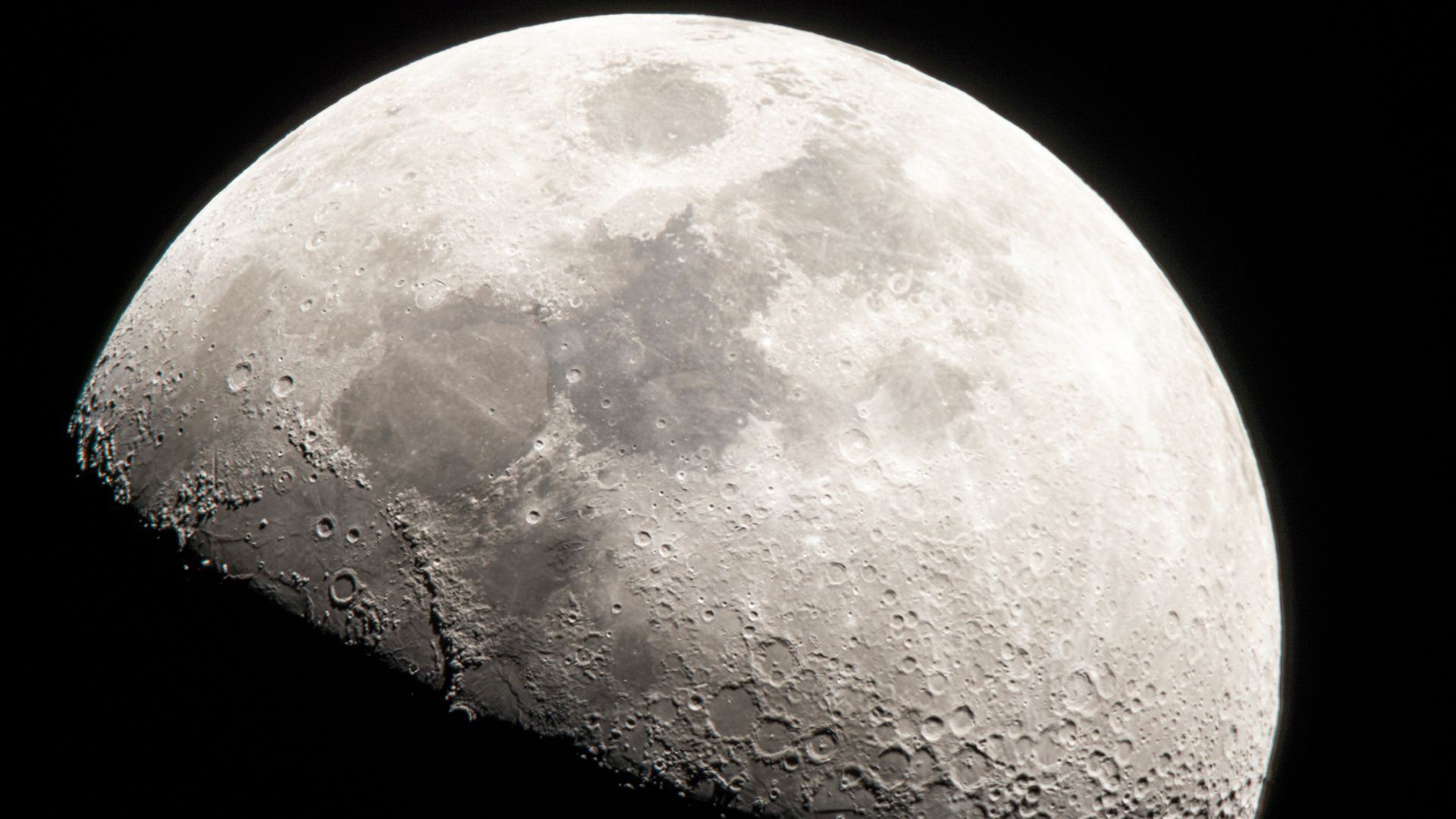 Detailed closeup photograph of the moon's cratered northern hemisphere against black space