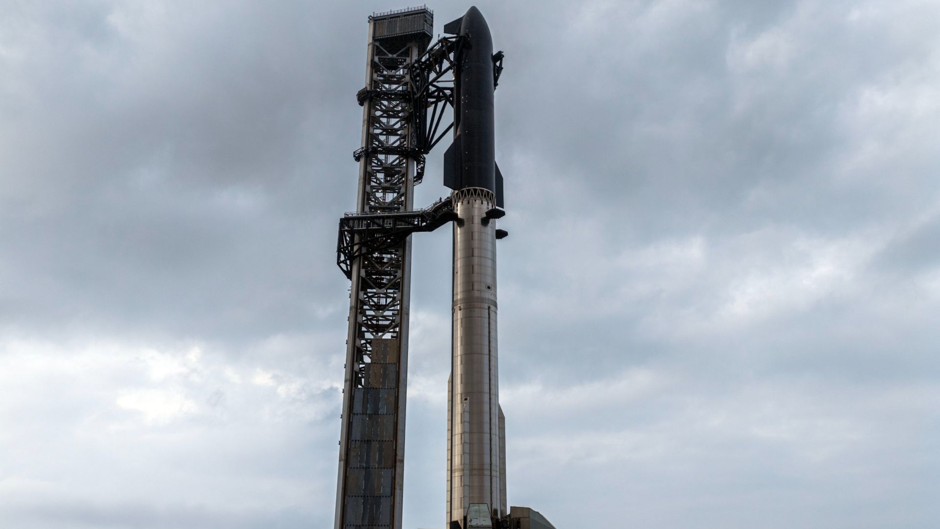** Massive silver SpaceX Starship V3 rocket standing on launch pad against blue sky