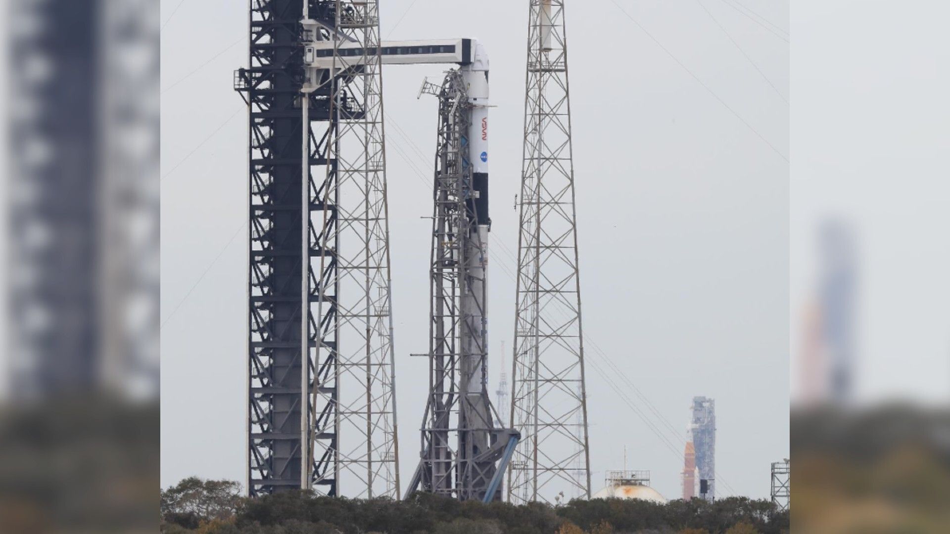 SpaceX Falcon 9 rocket stands before NASA's massive orange Artemis 2 moon rocket at Kennedy Space Center