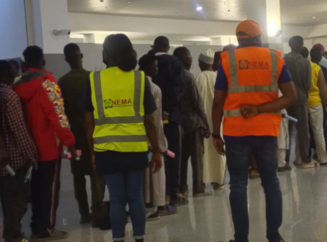 Nigerian returnees from Niger Republic receiving assistance from NEMA staff at Kano airport