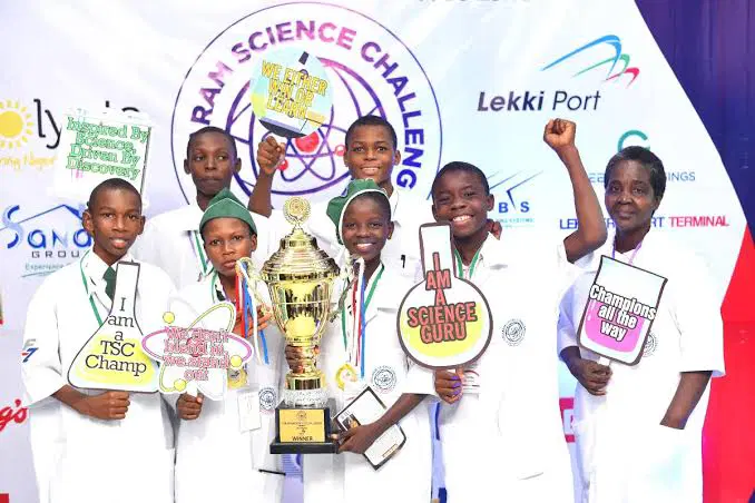 Nigerian students celebrating science competition victory with trophy and smiling faces in Lagos