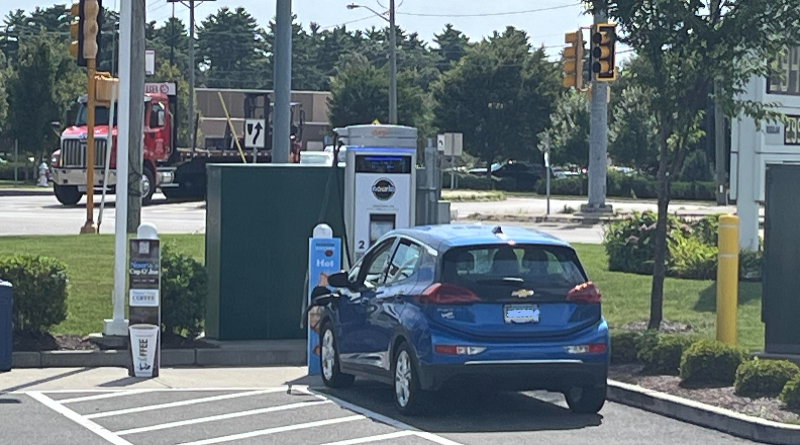 Electric vehicle charging station with power lines in background showing smart grid technology