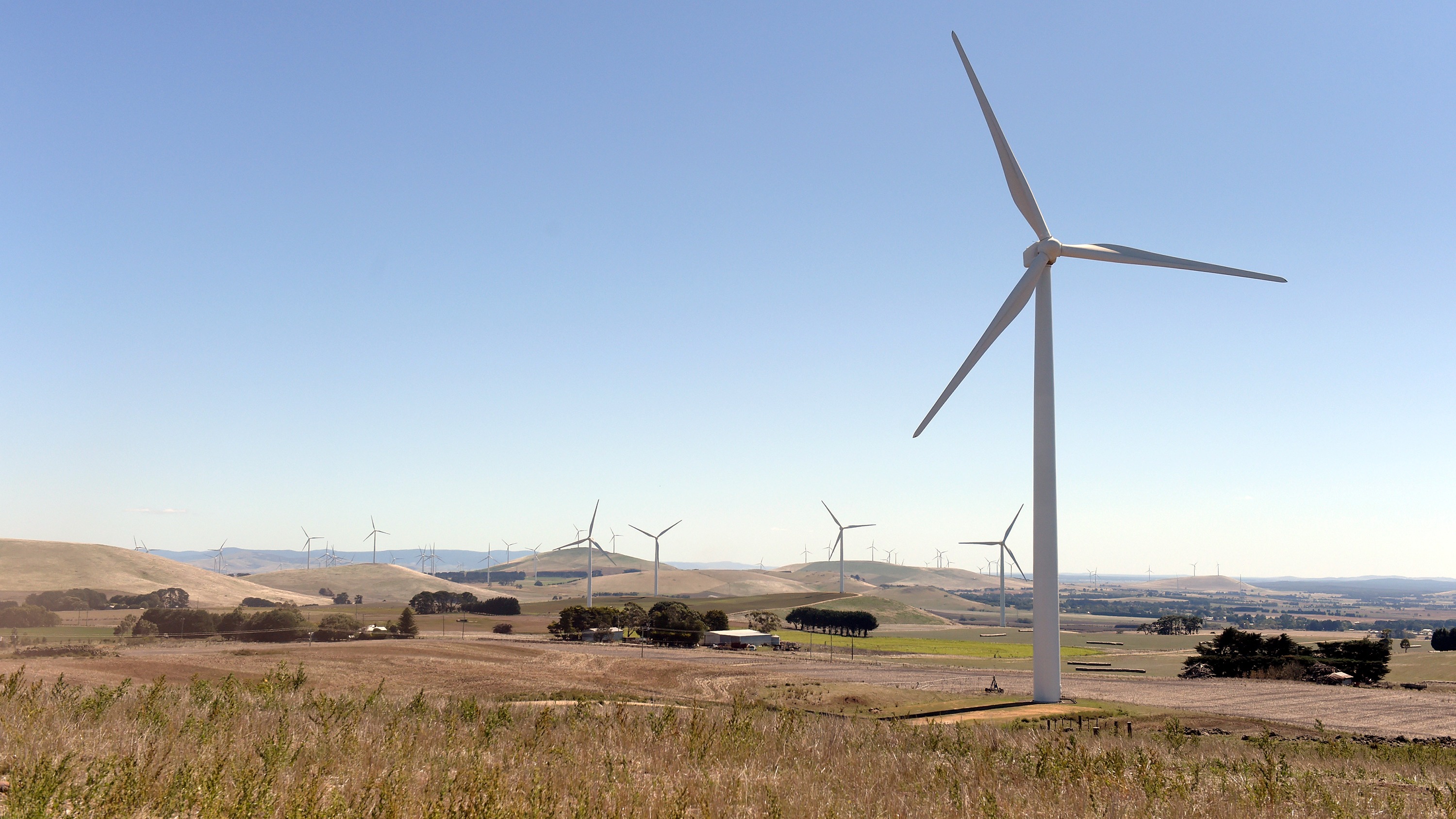 ** Wind turbines standing tall against blue sky in Queensland Australia renewable energy project