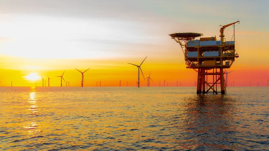 ** Offshore wind turbines spinning against blue sky over British coastal waters generating clean electricity