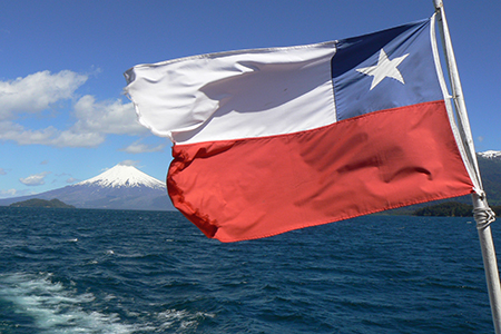 Solar panels stretching across Chilean landscape with wind turbines and battery storage facilities