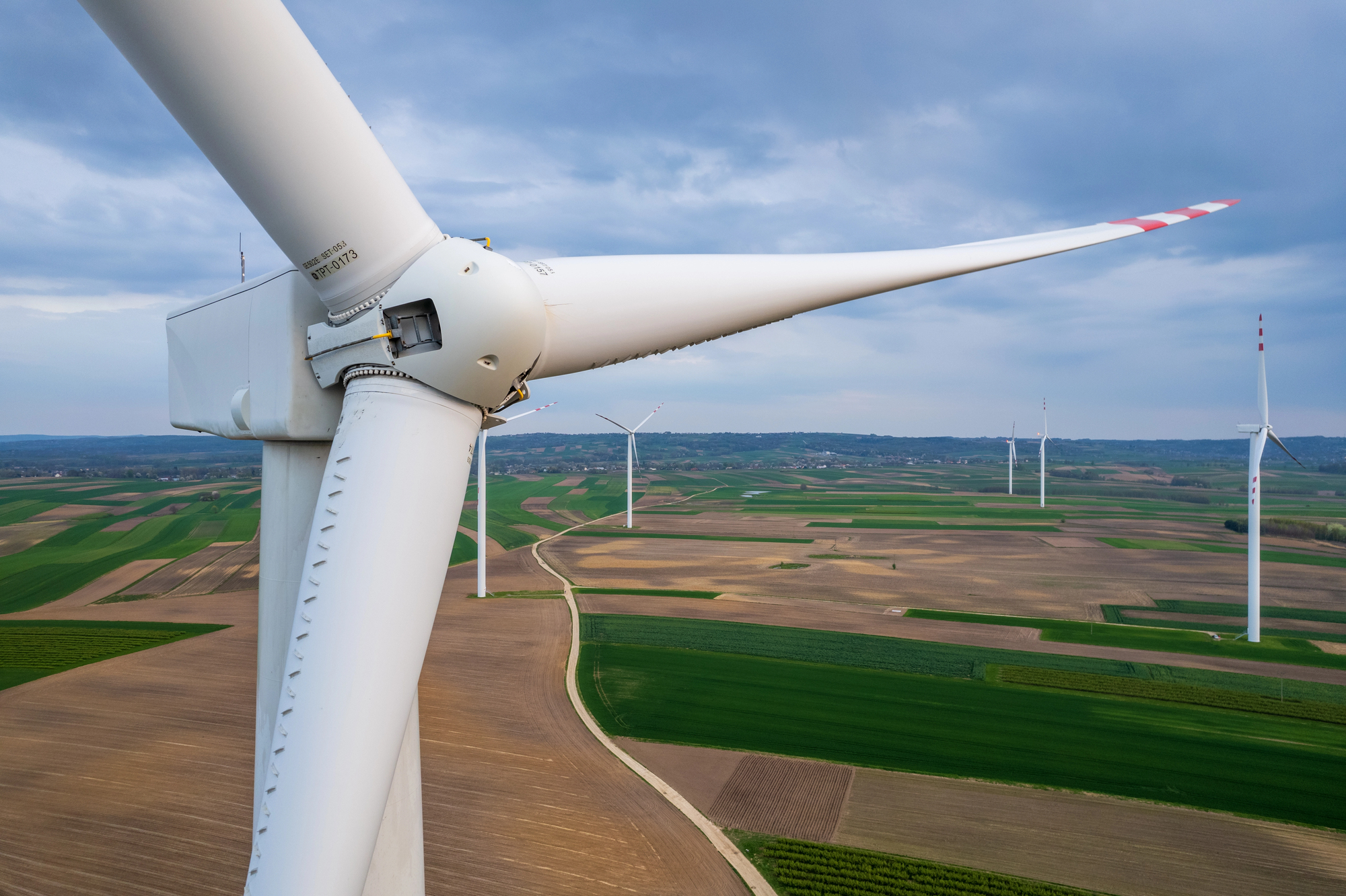 Tall white wind turbines standing in an open field generating renewable electricity for homes