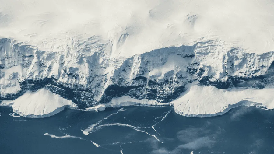 Aerial view of Antarctica's vast white ice sheet covering ancient geological structures beneath