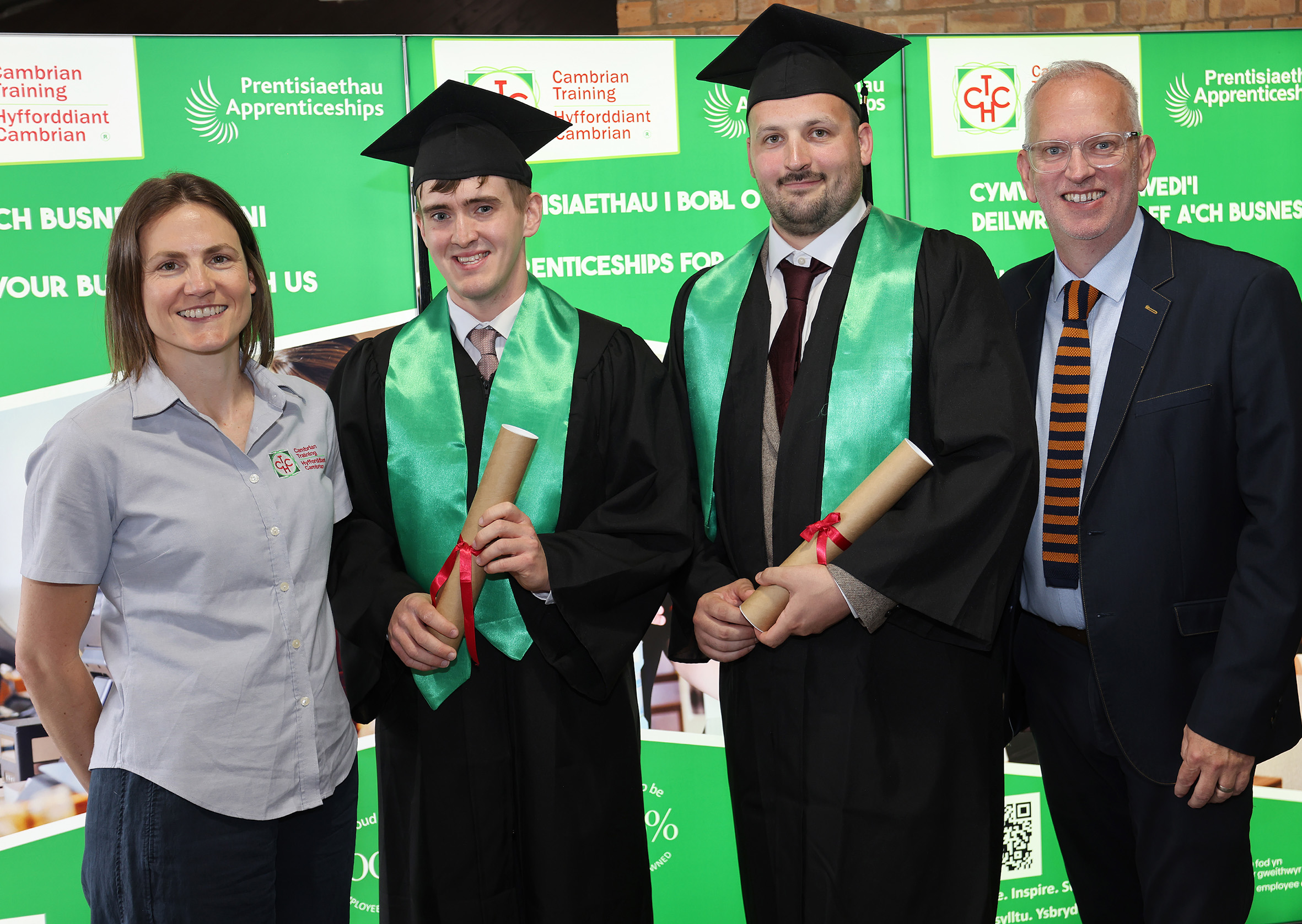 Five apprenticeship graduates in professional attire celebrating at graduation ceremony in Wales