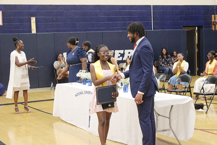Middle school principal Barrington Atkins speaking to students at assembly with microphone in hand