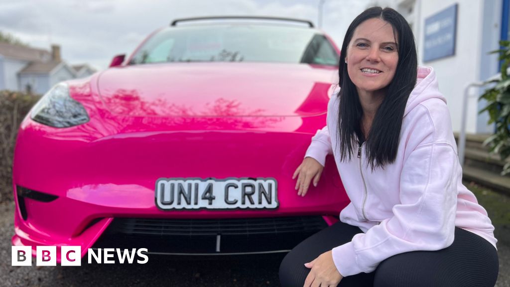 Bright pink Tesla Model Y with custom heart-shaped exhausts and unicorn-themed decorations parked in Essex