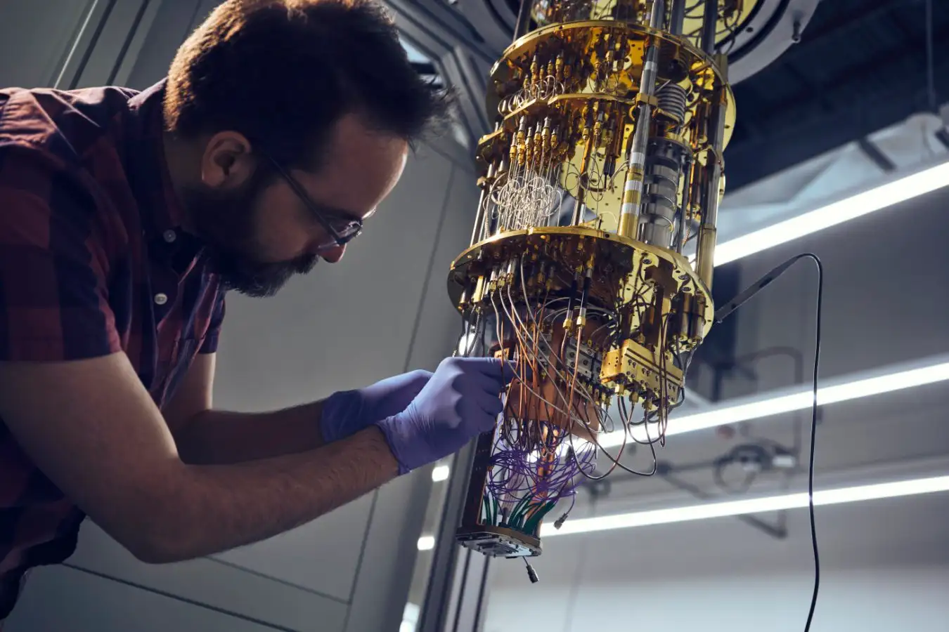 Technician in protective suit working with quantum computing chips in yellow-lit clean room facility