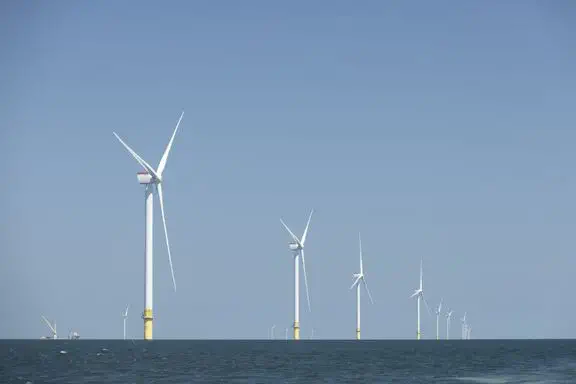 Offshore wind turbines spinning against blue sky generating clean electricity for New England homes