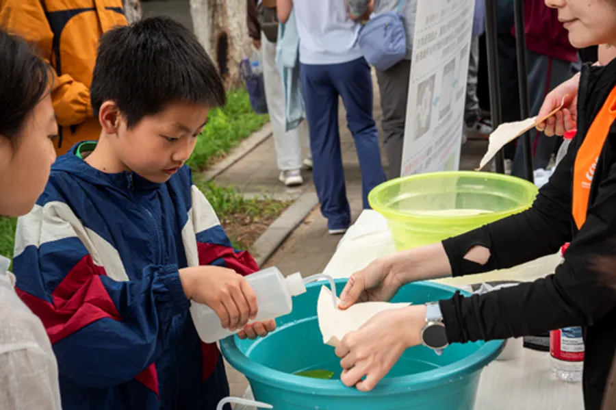 Student experimenting with water-resistant paper during hands-on science activity at Chinese research facility