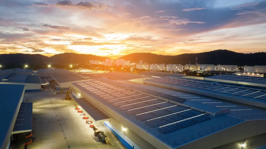 Solar panels installed on large commercial building rooftop under bright blue sky in India
