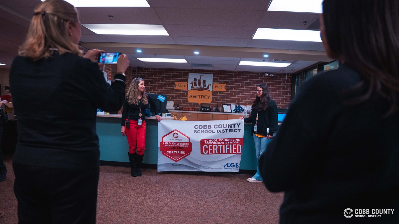 School counselors celebrating certification with students in bright, welcoming school hallway