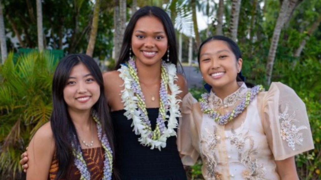 Three young women scholarship recipients smiling together holding certificates from Grove Farm Foundation