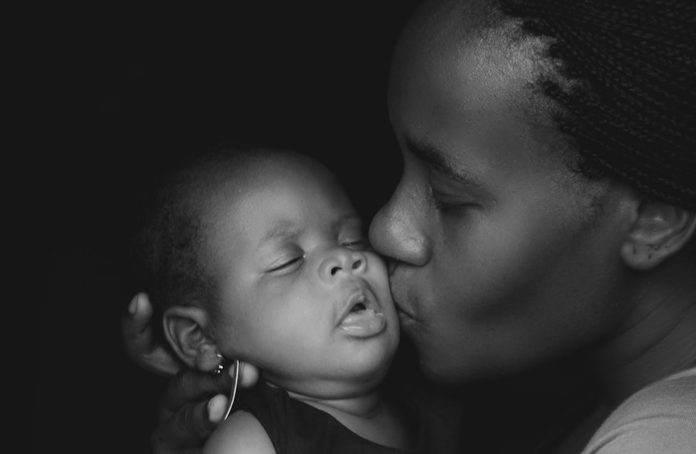 Mother holding healthy newborn baby in healthcare facility receiving quality maternal care services