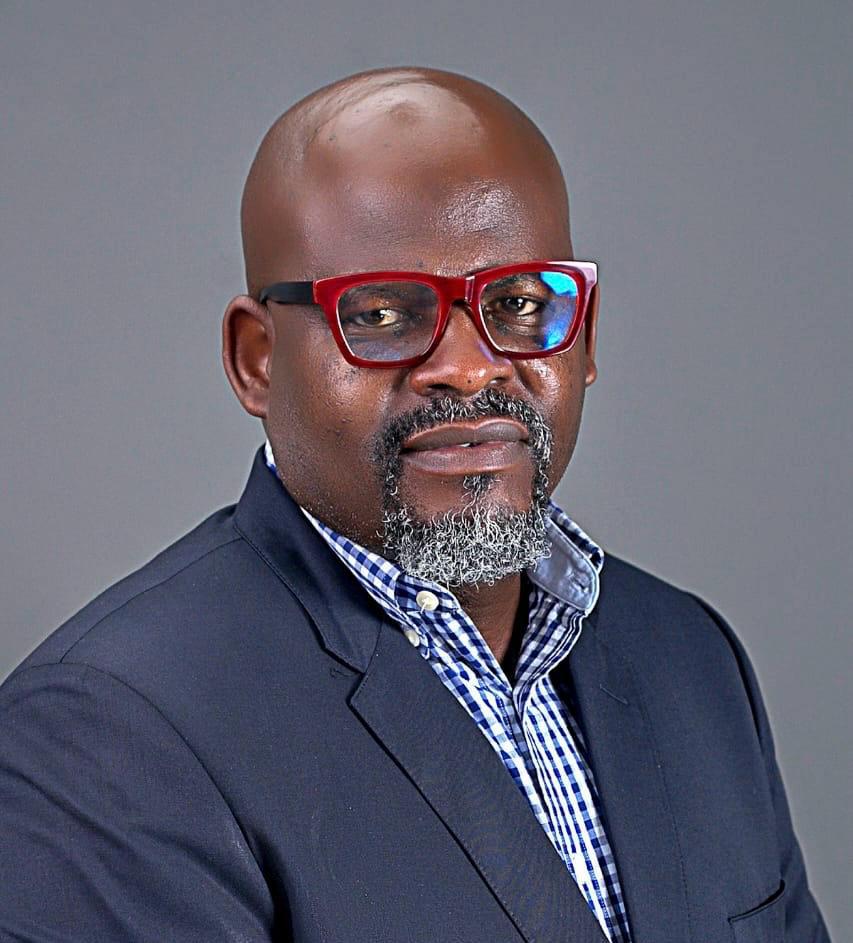 ** Boss Mustapha working at desk reviewing government documents in Nigerian federal office