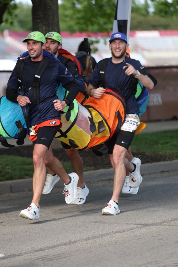 Five runners in connected green caterpillar costume crossing finish line at Indianapolis marathon
