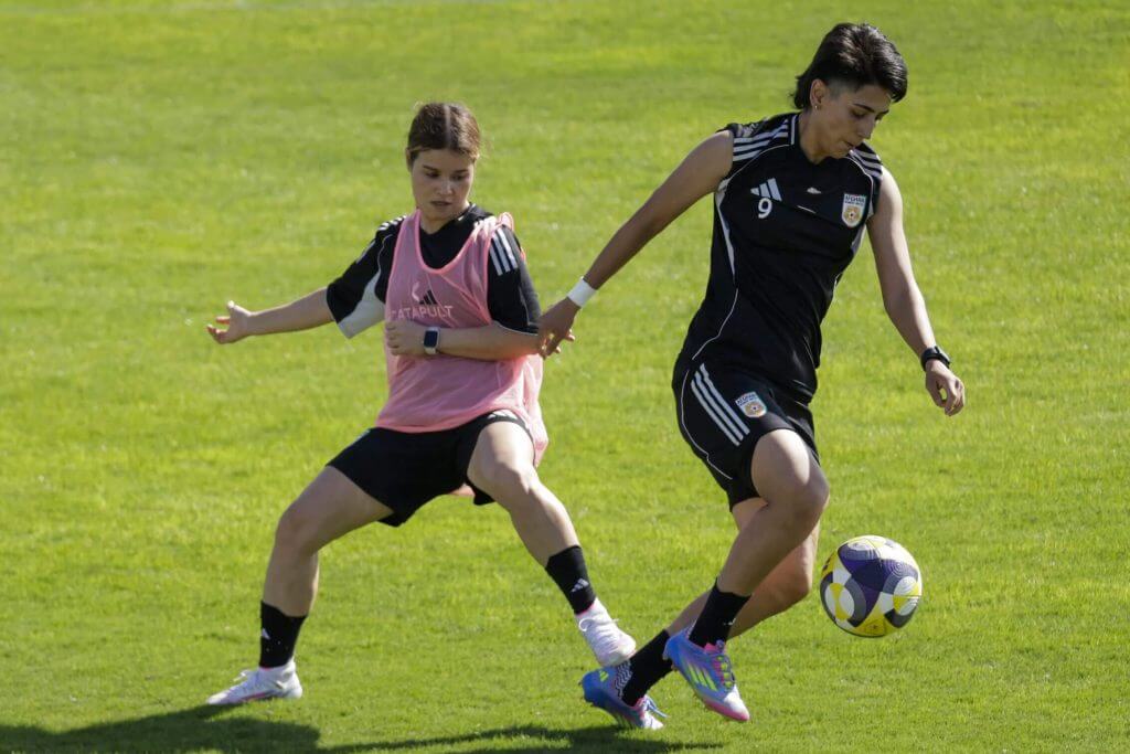Afghan women footballers in uniform celebrating together on the field during international competition