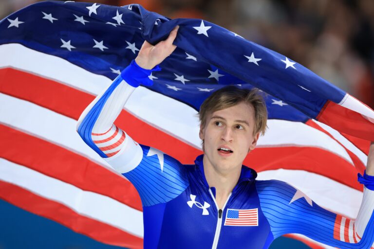 American speedskater Jordan Stolz racing in blue suit on ice at 2026 Winter Olympics