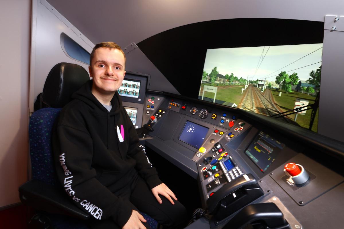 Teenage boy Jack Thompson smiling in train driver's seat at railway training center