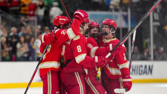 Denver Pioneers hockey players celebrate on ice after double overtime victory at Frozen Four