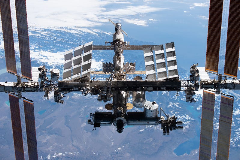 International Space Station orbiting above Earth's blue atmosphere against the darkness of space