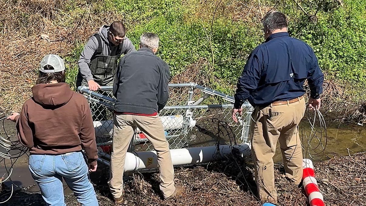 Volunteers installing a floating trash trap in a North Carolina river to collect plastic debris