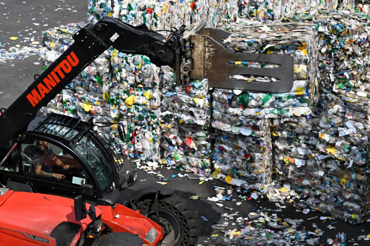 Clear plastic bottles lined up on recycling facility conveyor belt being sorted