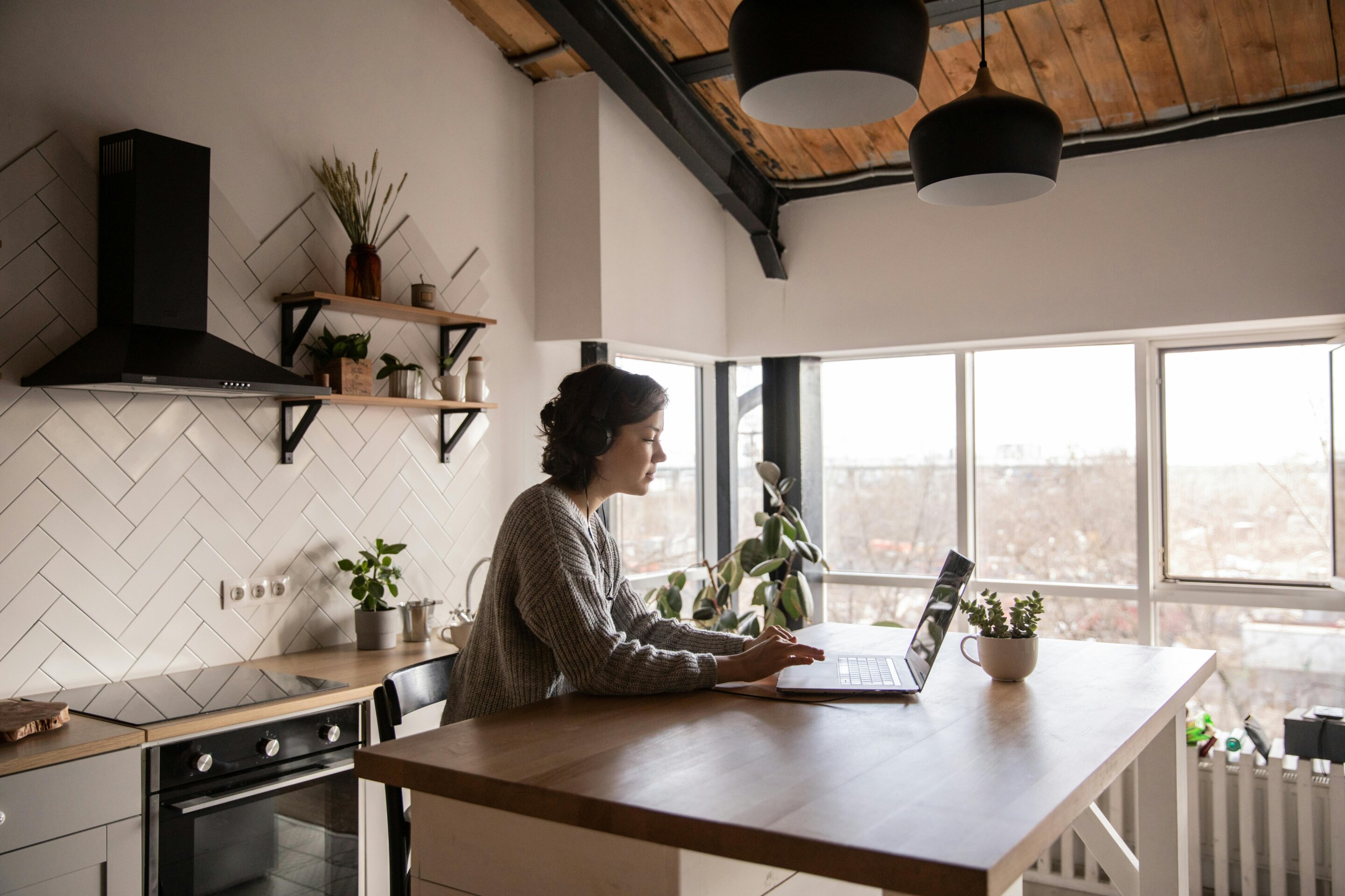 Professional working remotely on laptop at home office desk with natural lighting
