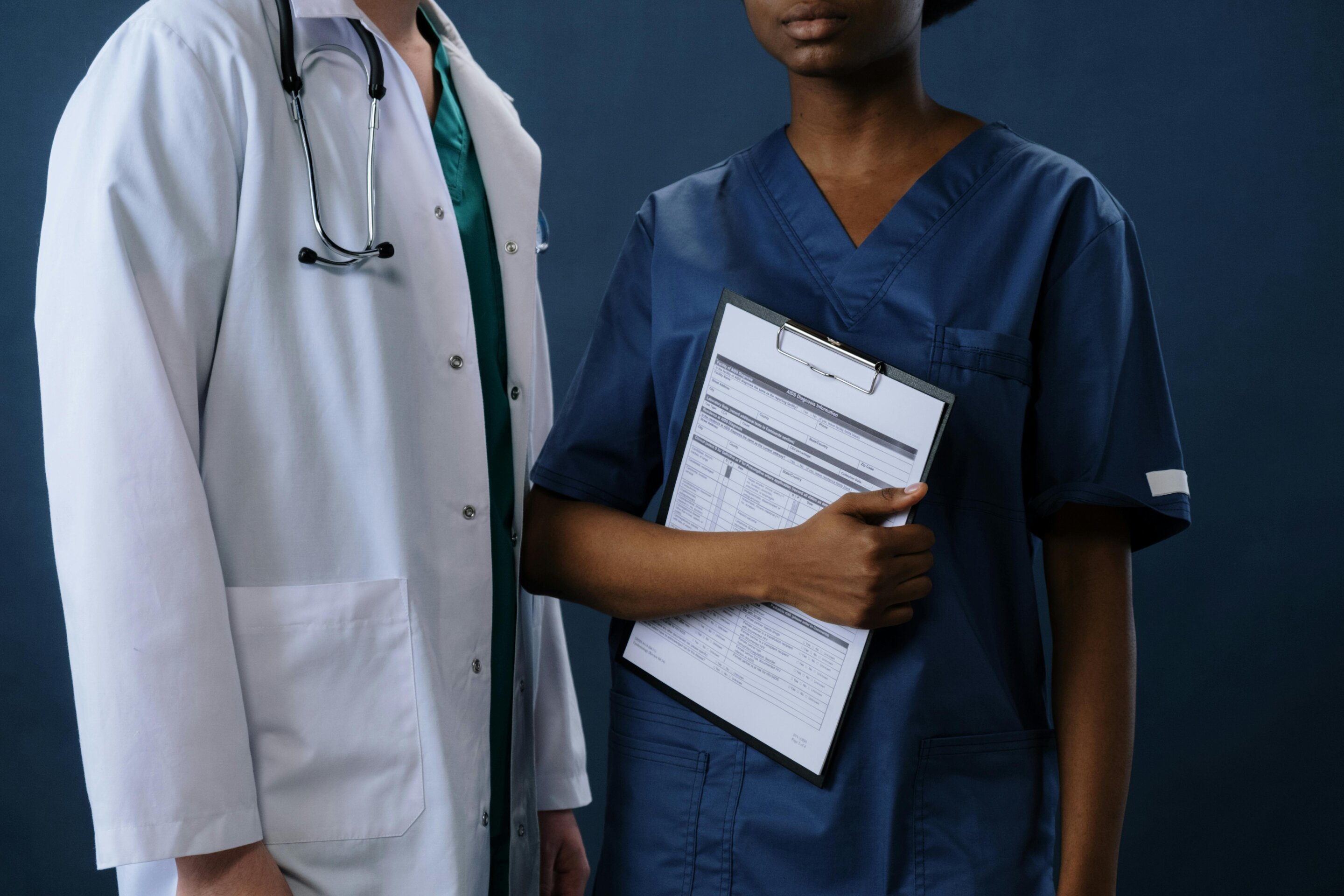 Smiling nurse in scrubs reviewing medical chart with patient in bright hospital room