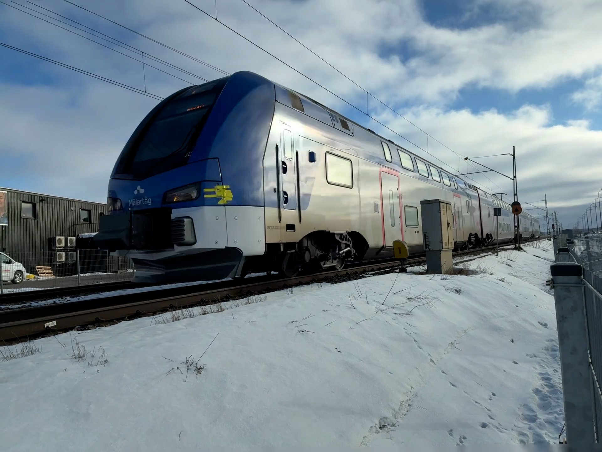 Commuter train traveling through snowy Swedish landscape toward Uppsala in winter daylight