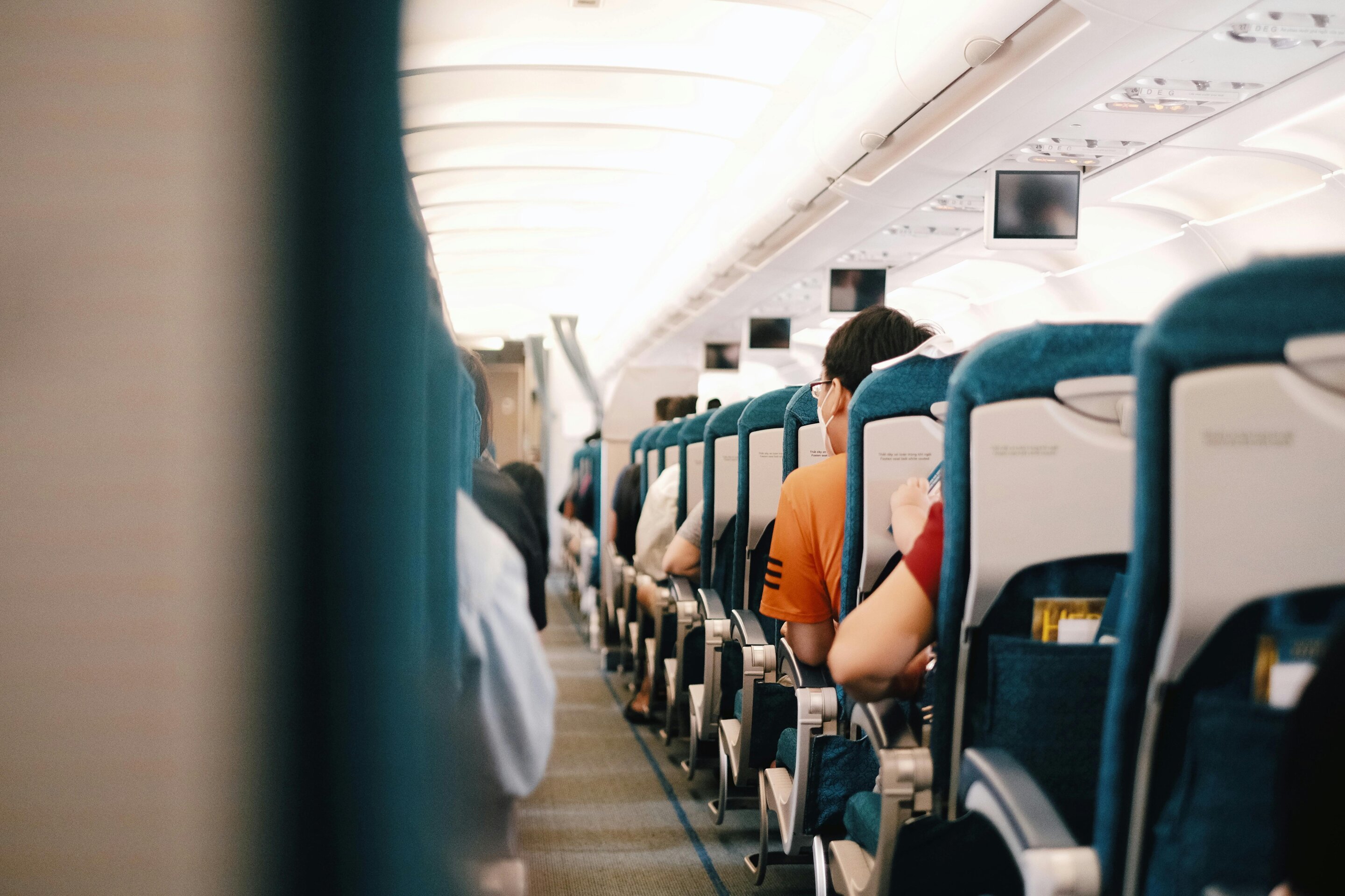 Interior view of commercial airplane cabin showing rows of economy seats filled with passengers