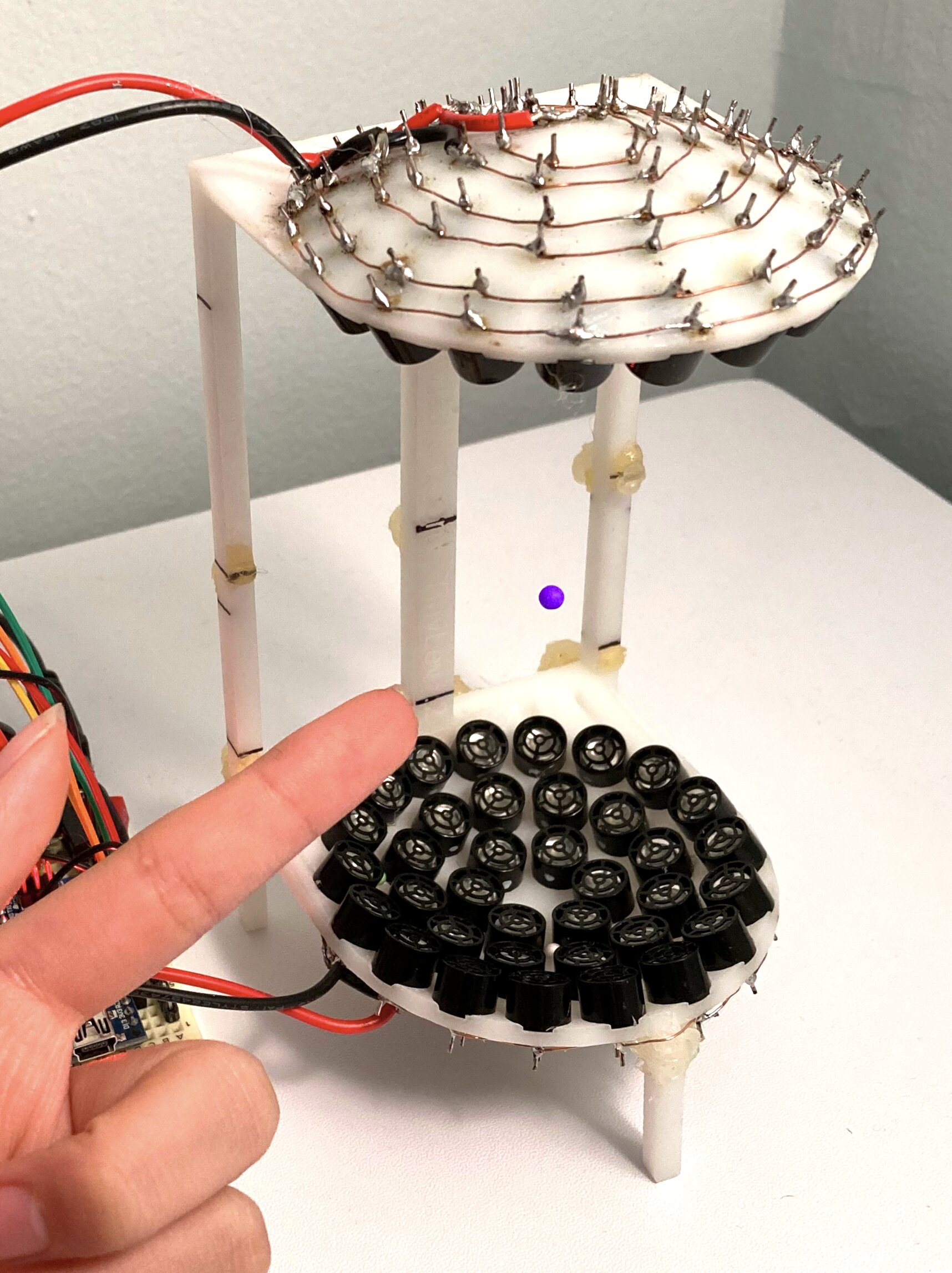 Purple styrofoam bead floating in mid-air above circular speakers in 3D-printed frame