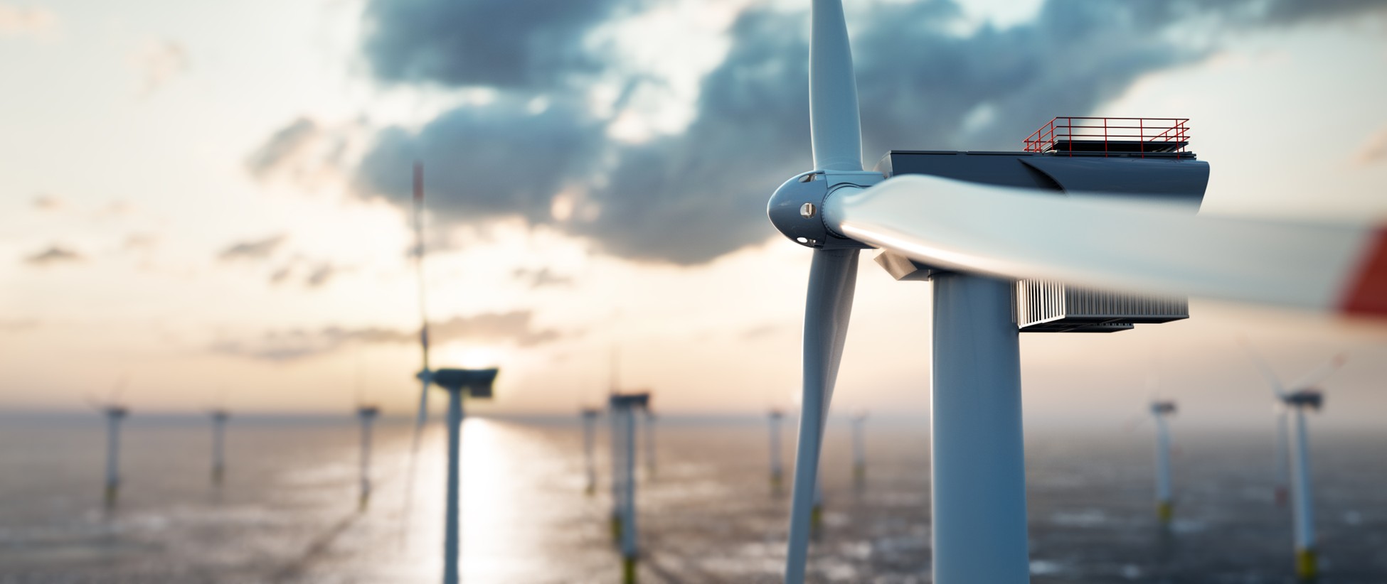 Massive offshore wind turbine towers above ocean waves against blue sky
