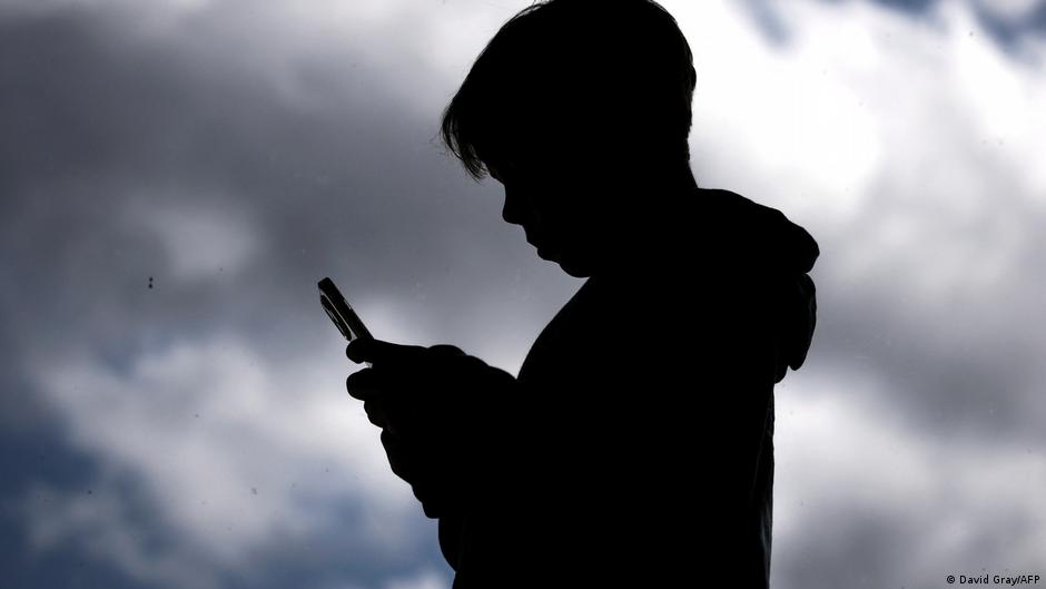 Teenagers looking at smartphones while discussing social media usage restrictions