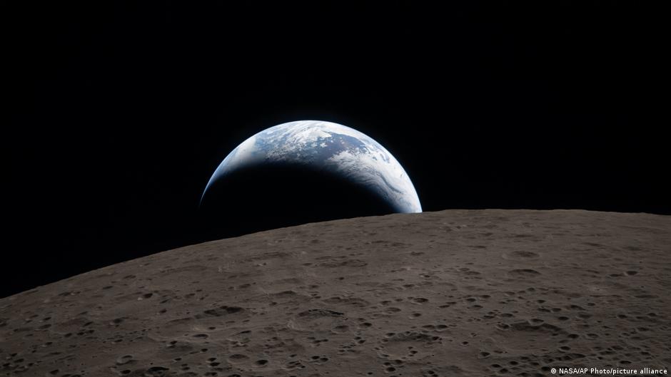 Earth setting below moon's horizon as seen from Artemis II spacecraft orbiting lunar surface