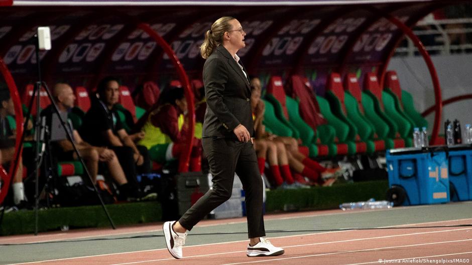 Female football coach standing on sideline during women's match in Africa