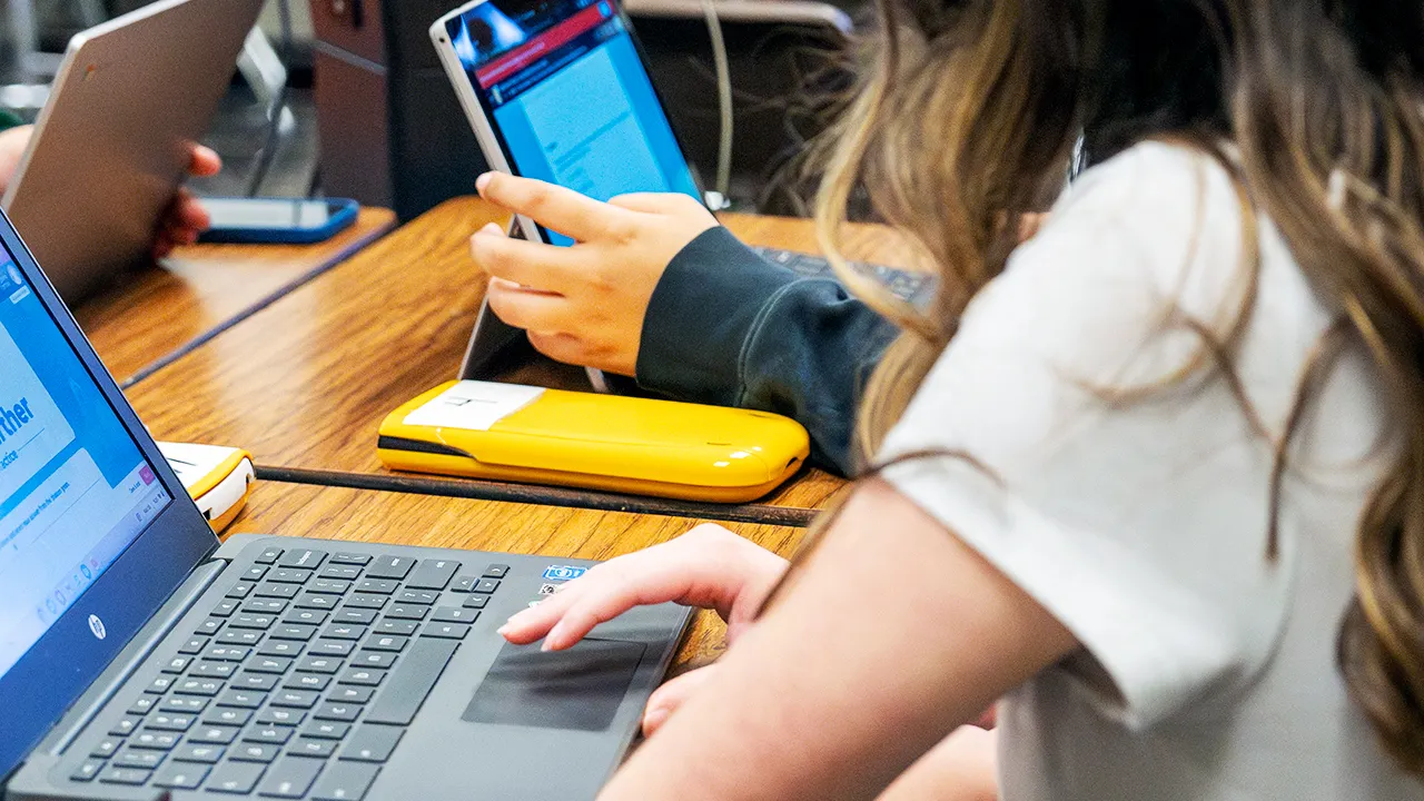 Students using laptops and tablets for writing assignments in modern classroom setting