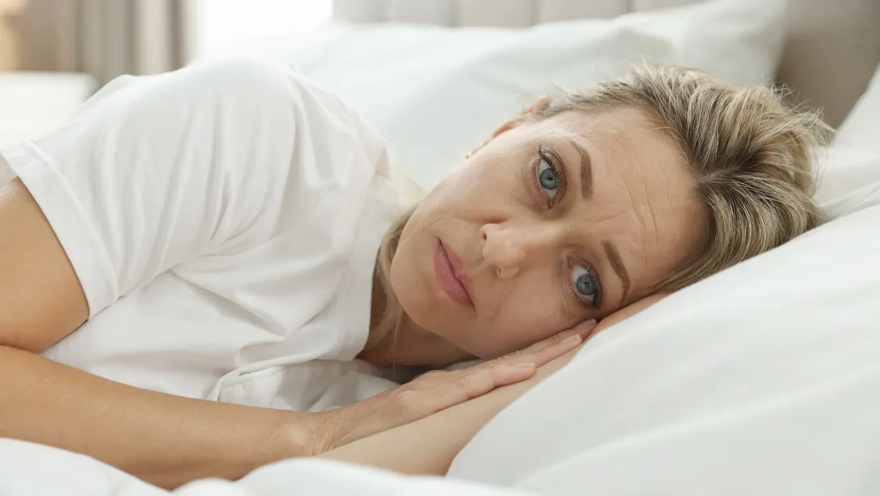 Person sleeping peacefully in bed with morning sunlight streaming through window