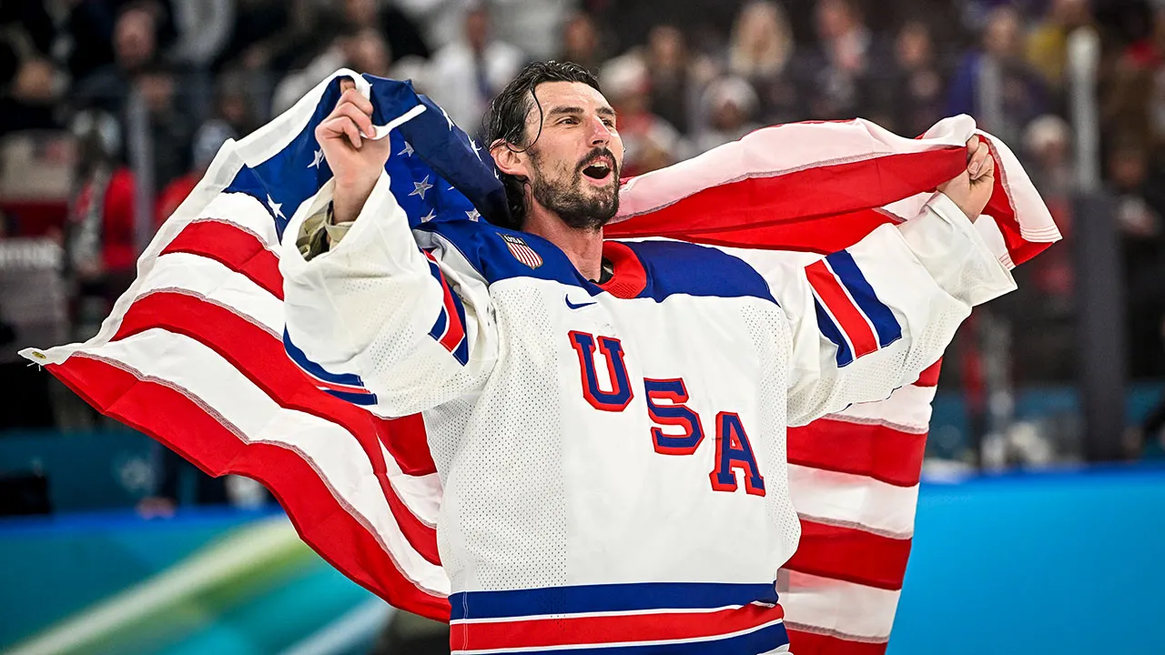 Olympic goaltender Connor Hellebuyck smiling while holding gold medal and Secretary of Defense plaque