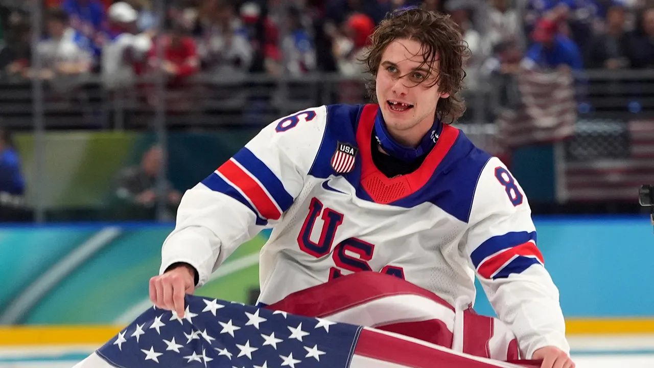 Jack Hughes celebrates with American flag after scoring overtime gold medal goal against Canada