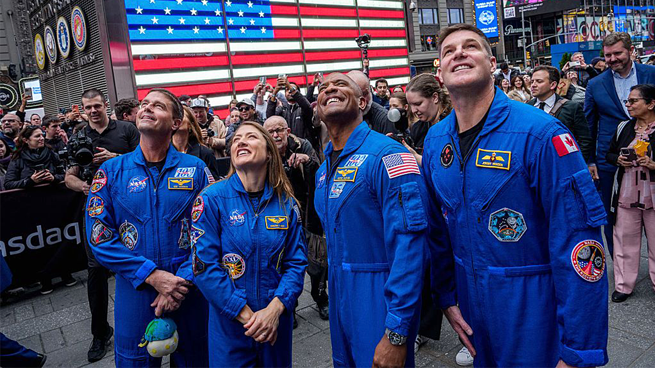 Four Artemis II astronauts in flight suits smiling together after historic Moon mission