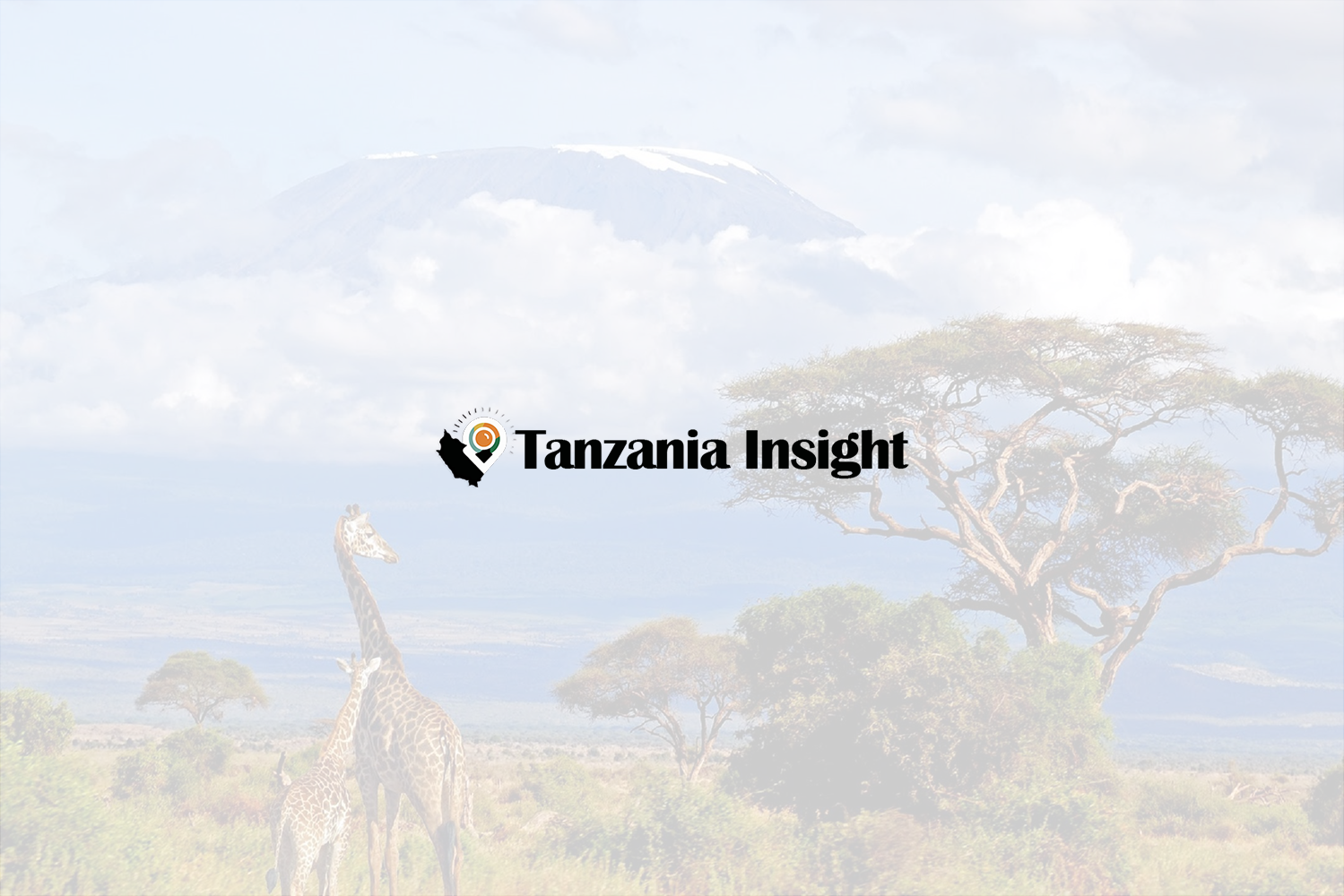 Snow-covered peak of Mount Kilimanjaro rising above green forests in Tanzania