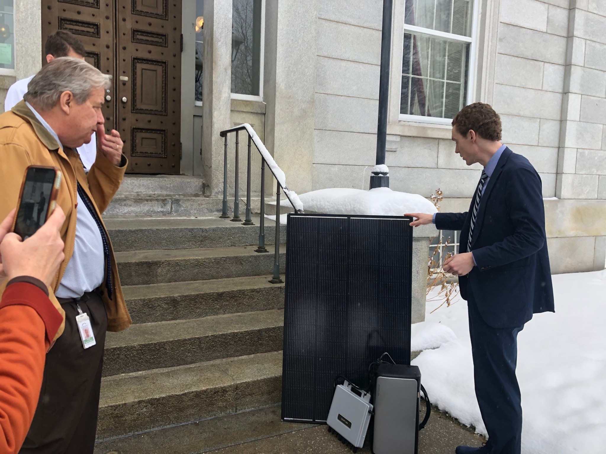 Ben Edgerly Walsh demonstrates small plug-in solar panel system to Vermont legislative committee members